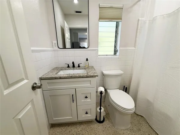 a bathroom with a granite countertop toilet sink and mirror