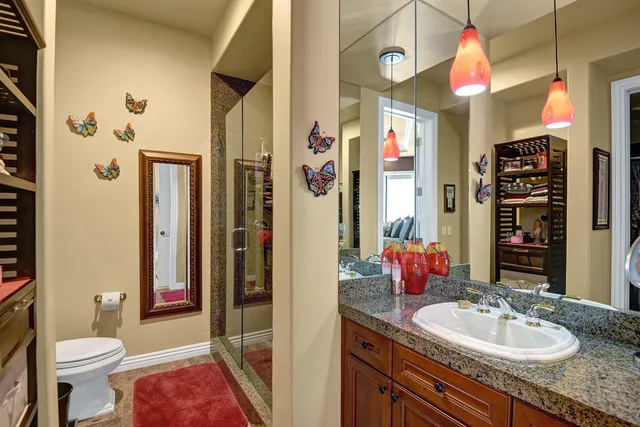 a bathroom with a granite countertop sink a toilet and shower