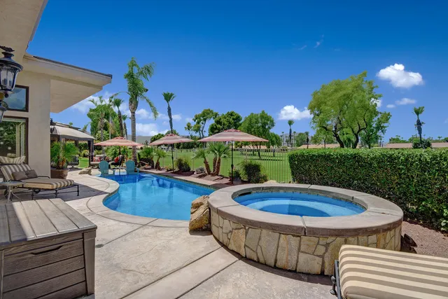 a view of a swimming pool with lawn chairs and a potted plant