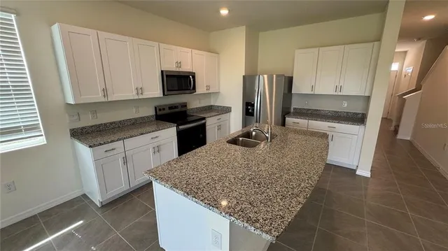 a kitchen with stainless steel appliances granite countertop a sink stove microwave and refrigerator