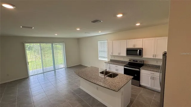 a kitchen with stainless steel appliances a sink a stove top oven a counter space and cabinets