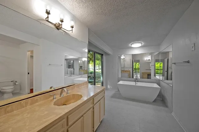 a spacious bathroom with a granite countertop sink and a bathtub