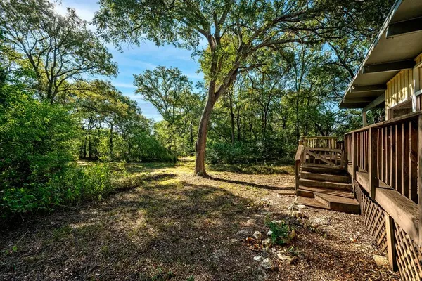 a view of a backyard with wooden fence and large trees