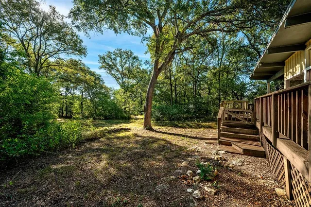 a view of a backyard with wooden fence and large trees