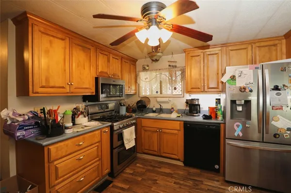 a kitchen with stainless steel appliances granite countertop a refrigerator a sink dishwasher a stove top oven a dining table and chairs with wooden floor
