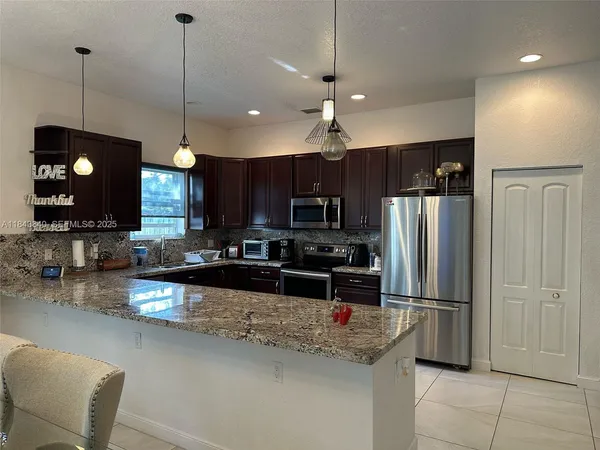 a kitchen with stainless steel appliances granite countertop a refrigerator a stove a sink and a microwave