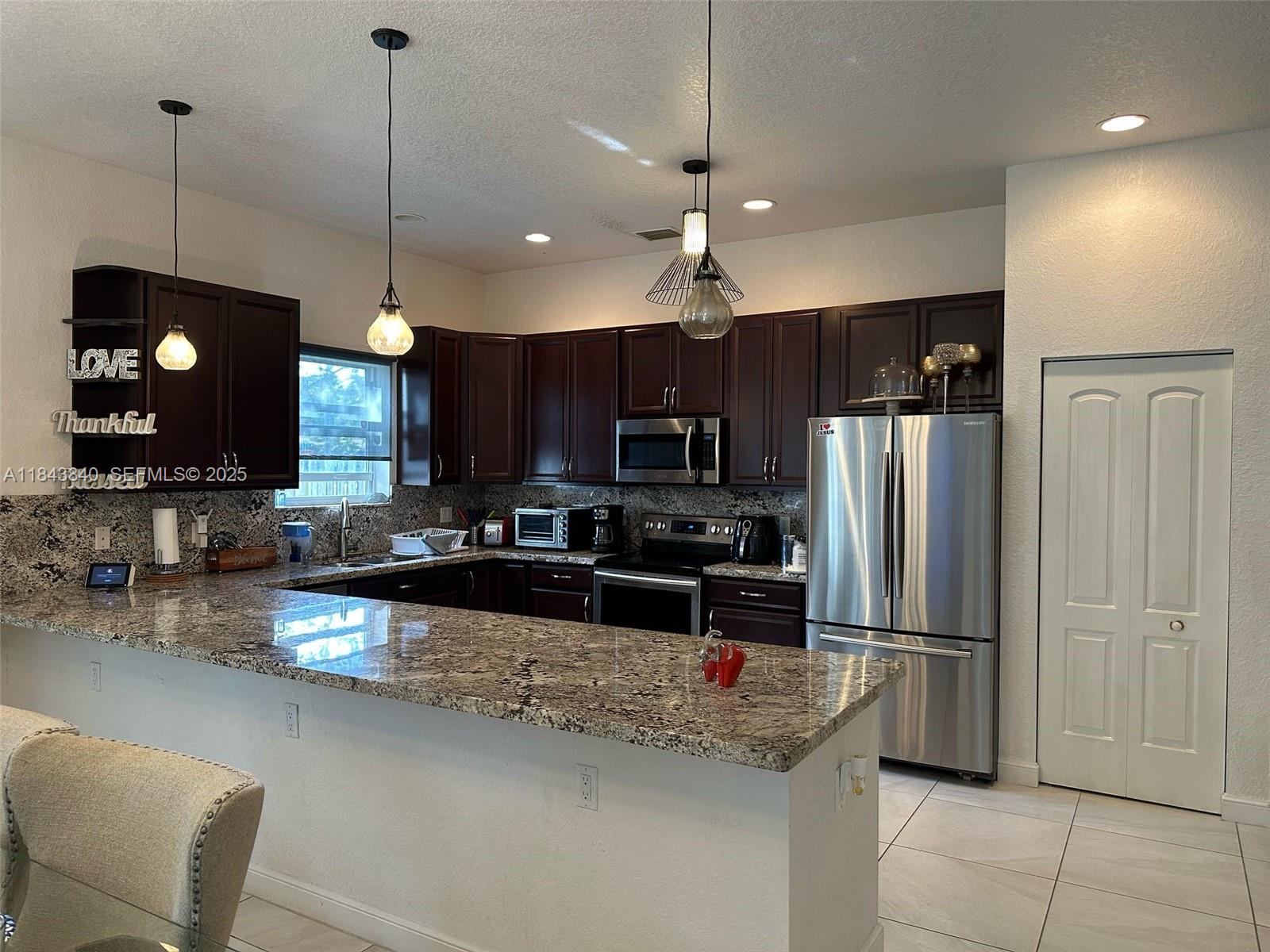 210 Southwest 4th Street, Unit 210 Dania Beach, FL 33004 - Photo 5 of 22 a kitchen with stainless steel appliances granite countertop a refrigerator a stove a sink and a microwave