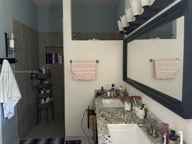 a bathroom with a granite countertop sink a mirror and shower