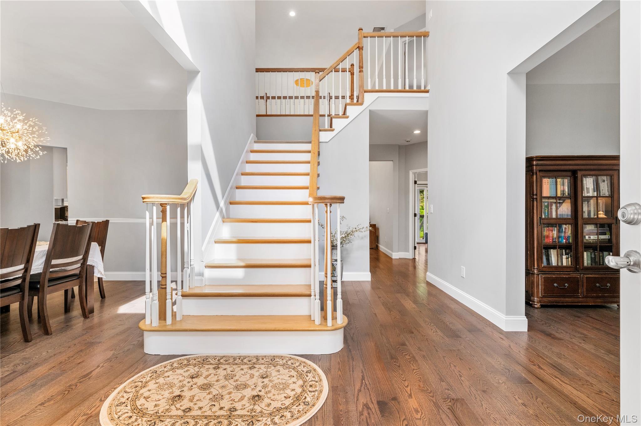 91 Bennetts Road East Setauket, NY 11733 - Photo 12 of 31 Staircase featuring wood finished floors, a high ceiling, and a chandelier