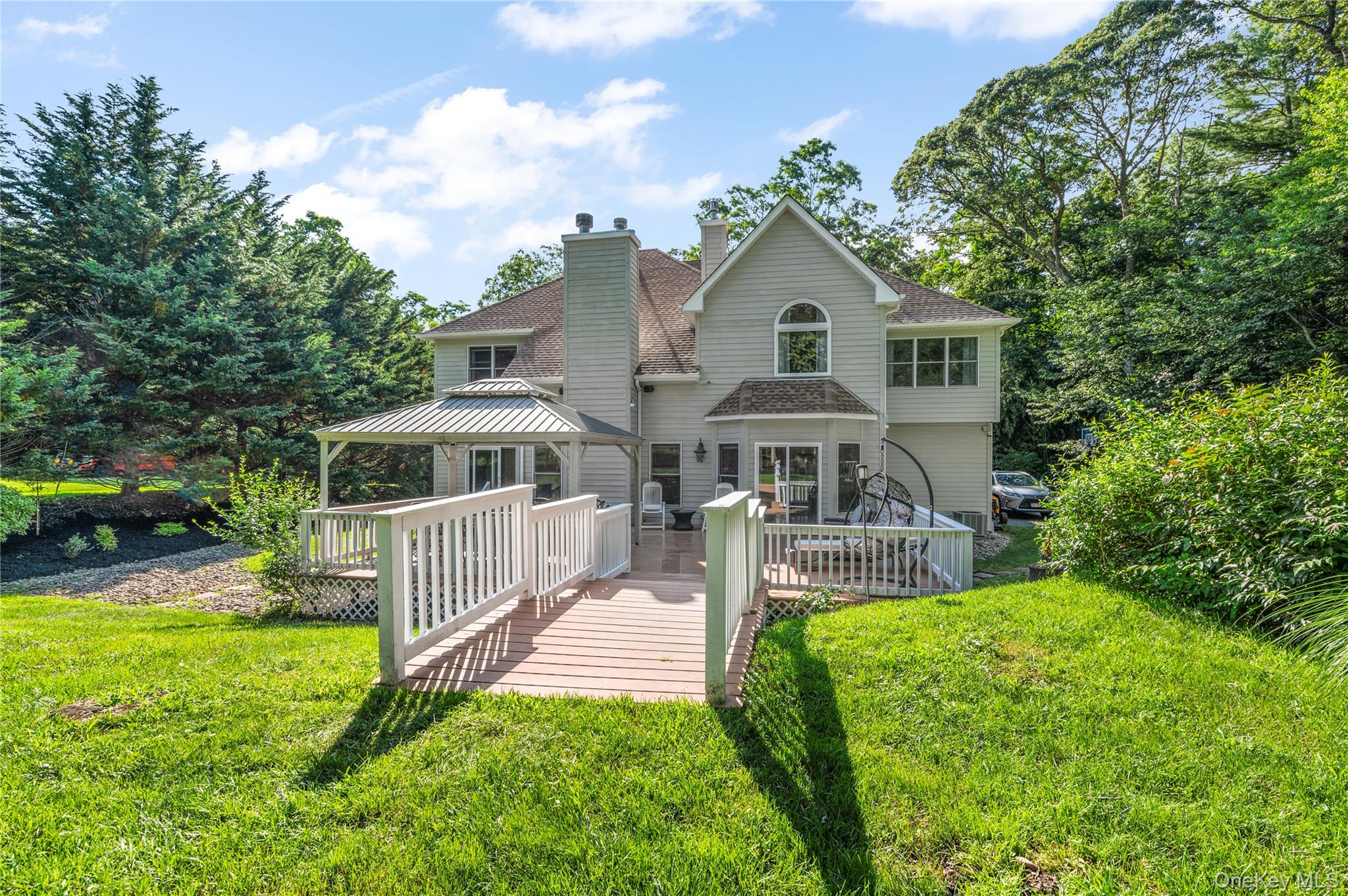 91 Bennetts Road East Setauket, NY 11733 - Photo 30 of 31 Rear view of house with a gazebo, a deck, a chimney, a lawn, and roof with shingles