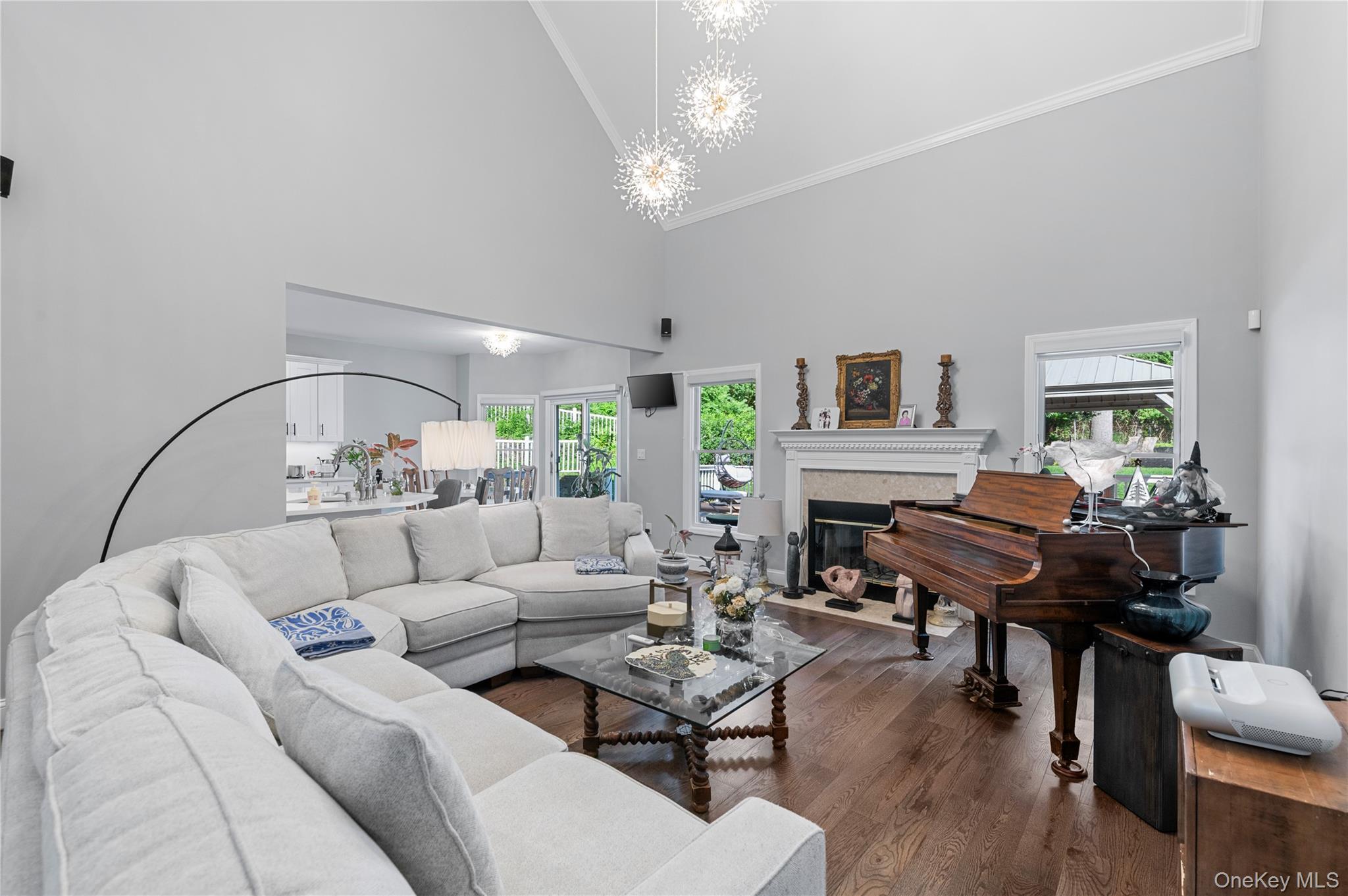 91 Bennetts Road East Setauket, NY 11733 - Photo 4 of 31 Living area with high vaulted ceiling, a chandelier, crown molding, healthy amount of natural light, and a fireplace with flush hearth