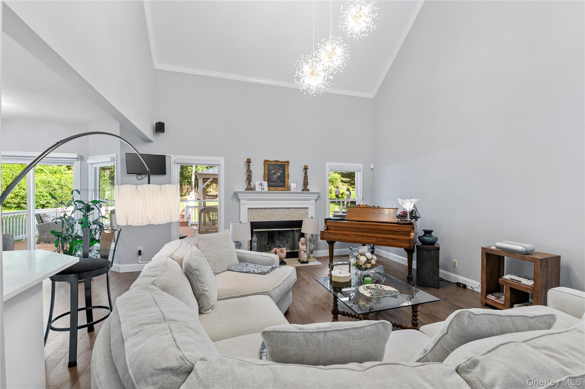 91 Bennetts Road East Setauket, NY 11733 - Photo 5 of 31 Living room featuring high vaulted ceiling, plenty of natural light, a chandelier, a glass covered fireplace, and crown molding