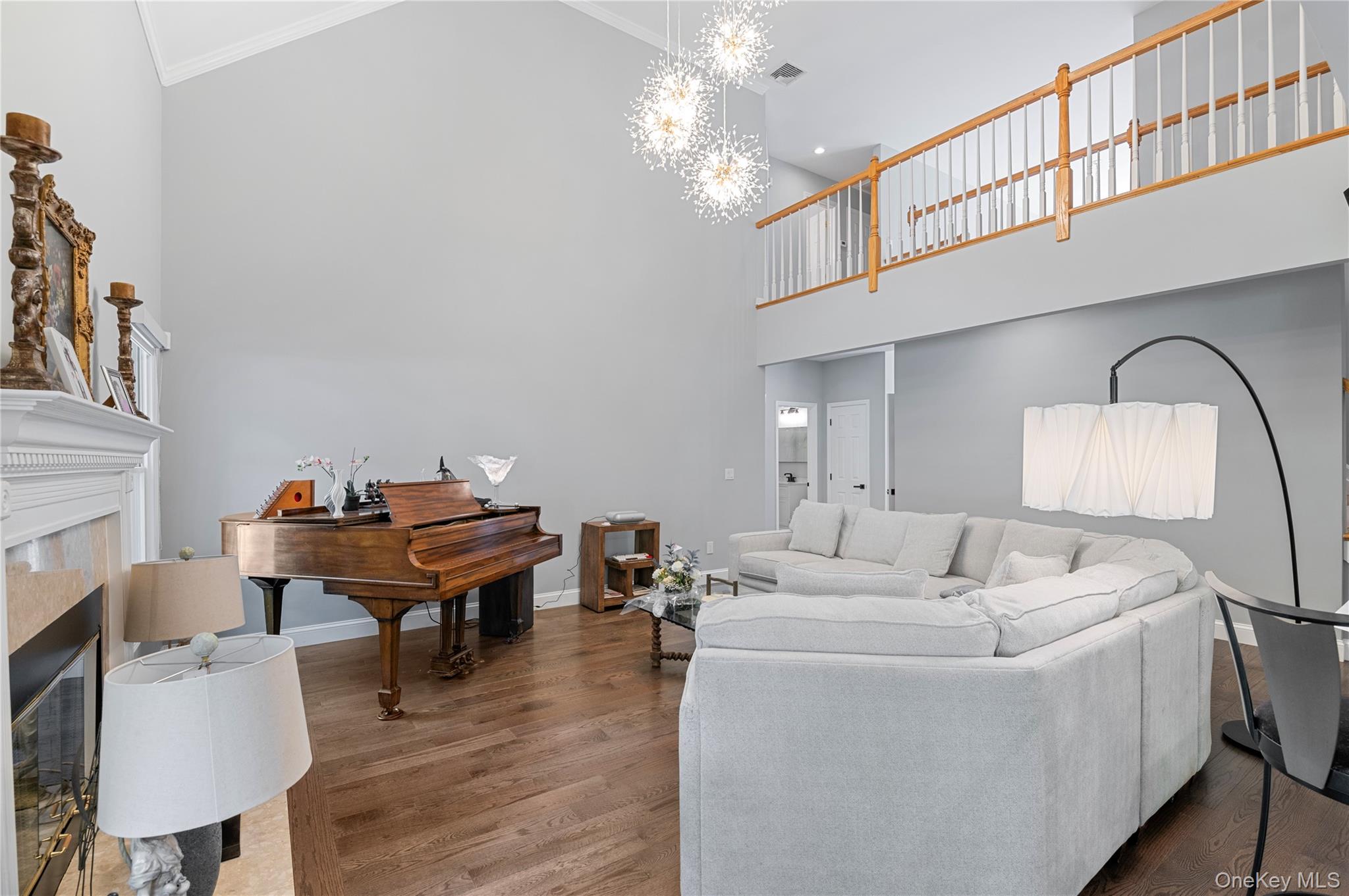 91 Bennetts Road East Setauket, NY 11733 - Photo 6 of 31 Living room with a high ceiling, a tile fireplace, ornamental molding, a chandelier, and wood finished floors