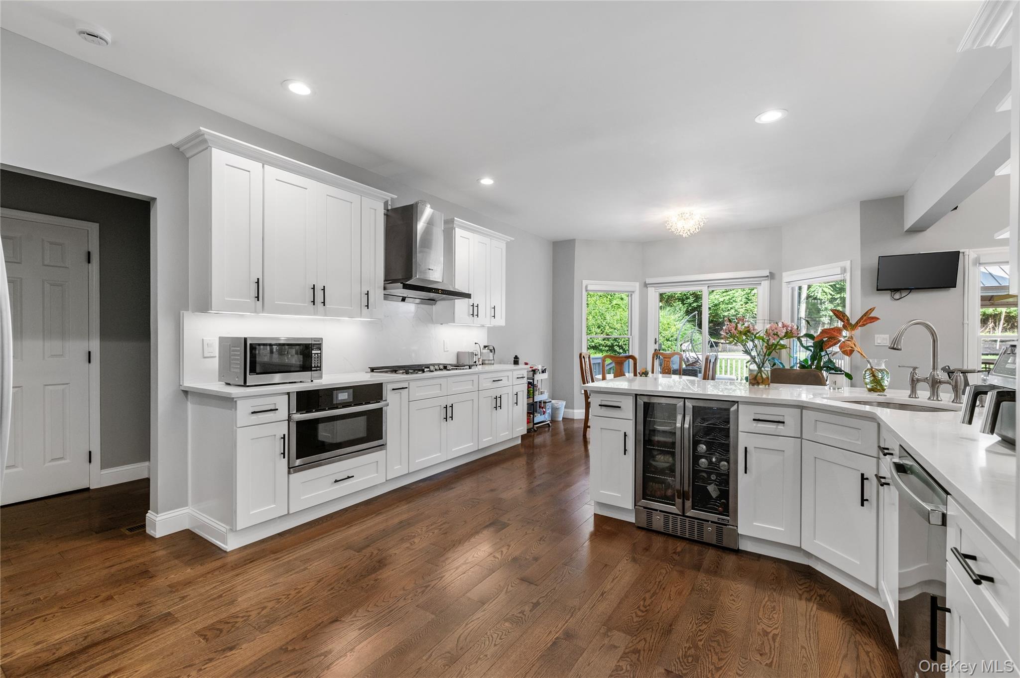 91 Bennetts Road East Setauket, NY 11733 - Photo 8 of 31 Kitchen with beverage cooler, appliances with stainless steel finishes, wall chimney rangehood, dark wood-style floors,and light countertops