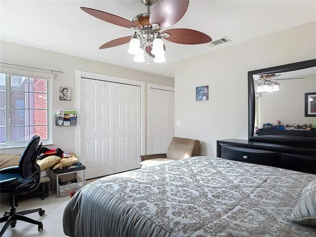 a view of an empty room with window and chandelier fan