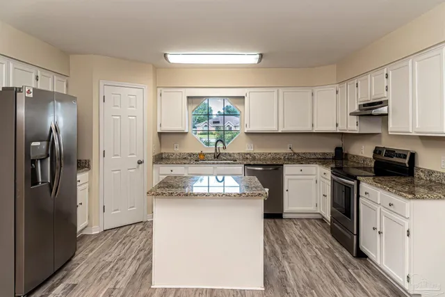 a kitchen with stainless steel appliances granite countertop a refrigerator sink and stove