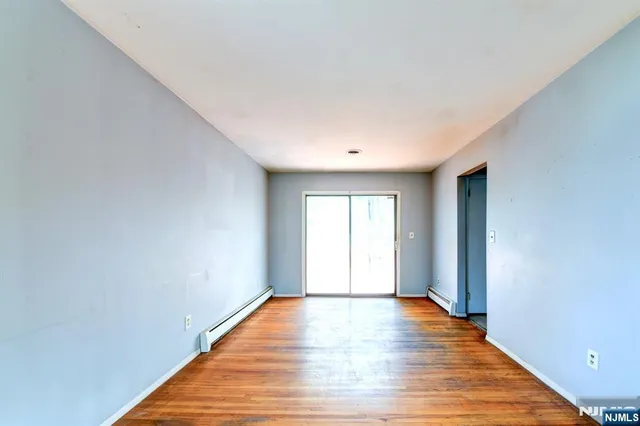 a view of an empty room with wooden floor and window
