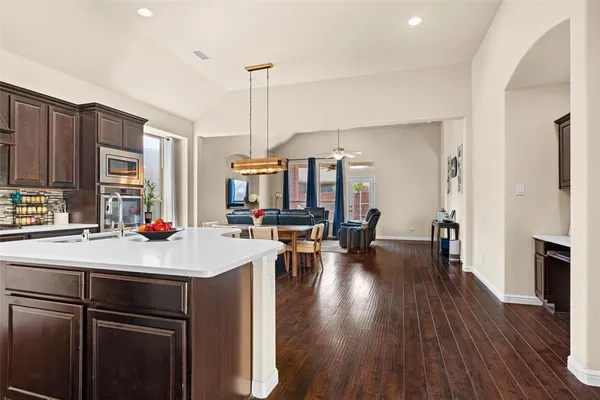 a room with kitchen island a wooden floor and white appliances
