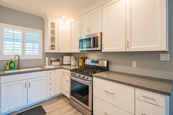 a kitchen with stainless steel appliances granite countertop white cabinets a sink and a stove