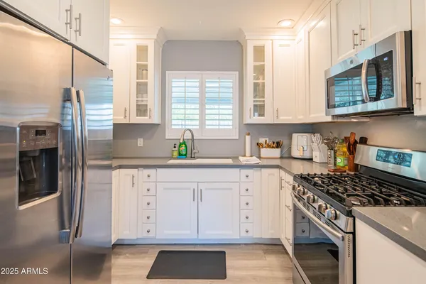 a kitchen with granite countertop white cabinets stainless steel appliances a sink and a window