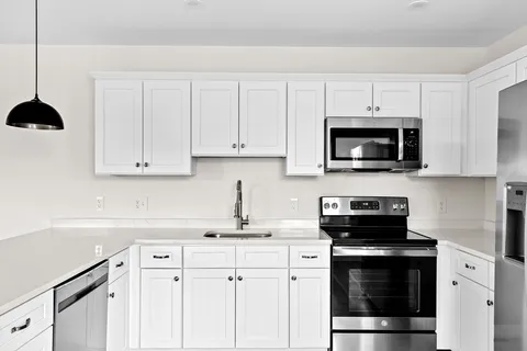 a kitchen with stainless steel appliances granite countertop white cabinets a stove a sink and dishwasher