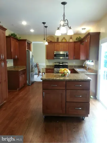 a kitchen with stainless steel appliances granite countertop a stove a refrigerator and a wooden cabinets