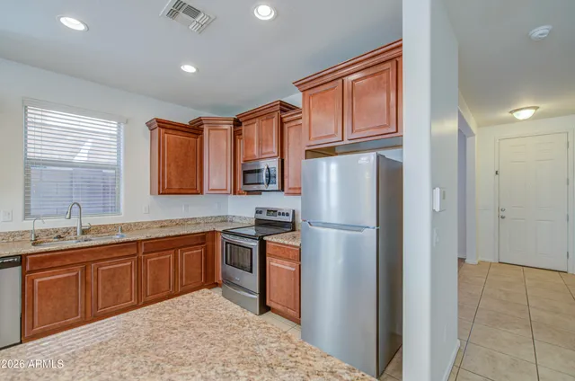 a kitchen with stainless steel appliances granite countertop a refrigerator a sink dishwasher a stove with wooden cabinets