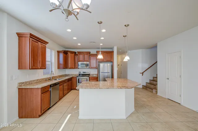 a large kitchen with granite countertop a large counter top and stainless steel appliances