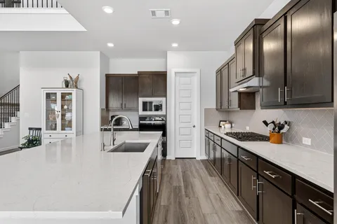 a kitchen with stainless steel appliances granite countertop a stove top oven a refrigerator a sink and dishwasher with wooden floor