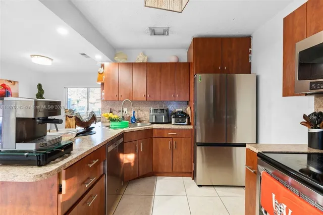 a kitchen with stainless steel appliances granite countertop a refrigerator stove a sink dishwasher and microwave