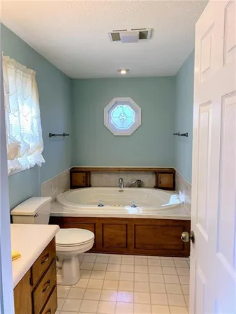 a en suite bathroom with a granite countertop toilet a sink and a window