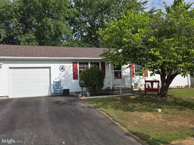 a front view of a house with a garden and trees