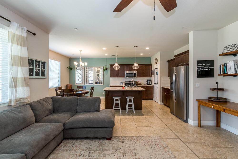 2731 Griffith Avenue Clovis, CA 93611 - Photo 13 of 34 a living room kitchen with stainless steel appliances kitchen island granite countertop a refrigerator a stove a sink a dining table and chairs with wooden floor