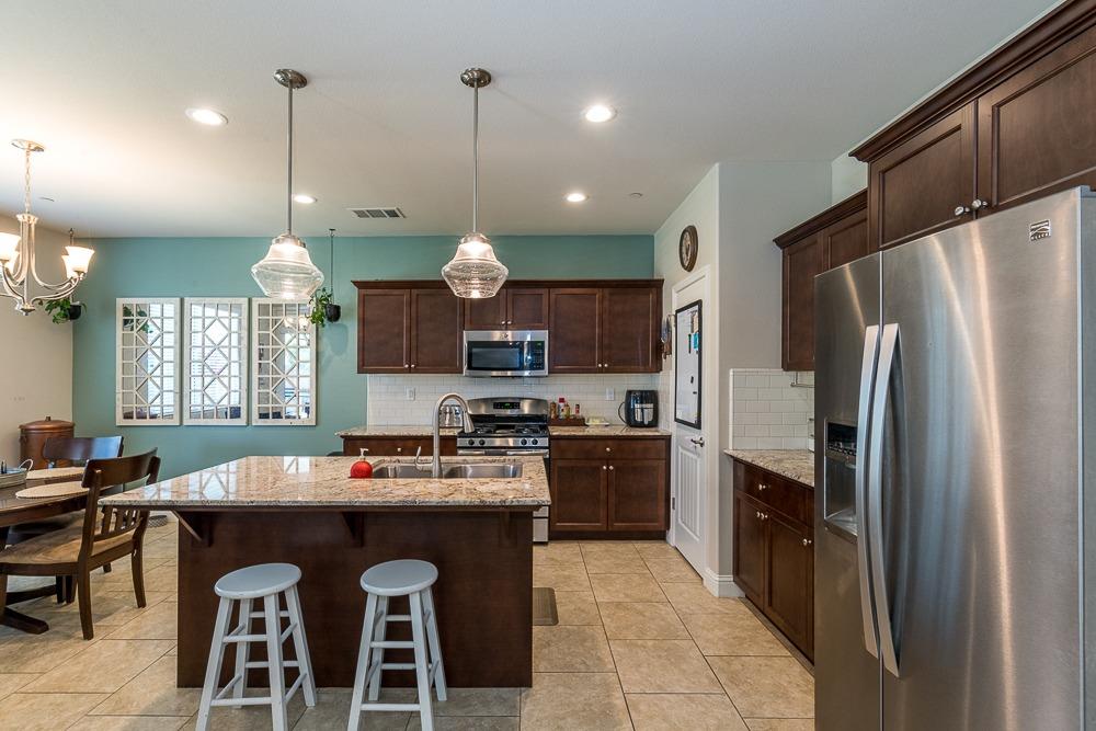 2731 Griffith Avenue Clovis, CA 93611 - Photo 18 of 34 a kitchen with granite countertop a table chairs stainless steel appliances and wooden floor