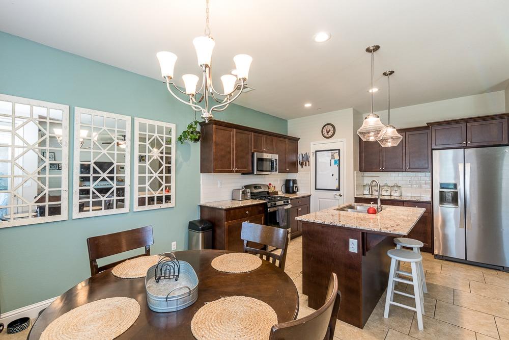 2731 Griffith Avenue Clovis, CA 93611 - Photo 24 of 34 a kitchen with a dining table cabinets stainless steel appliances and a chandelier