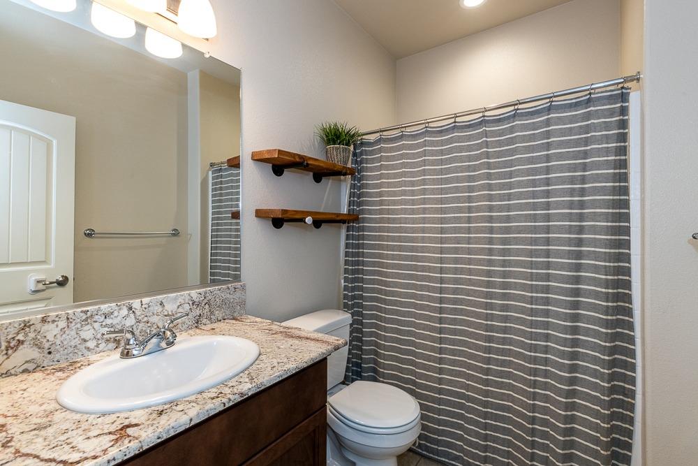 2731 Griffith Avenue Clovis, CA 93611 - Photo 31 of 34 a bathroom with a granite countertop toilet a sink and mirror