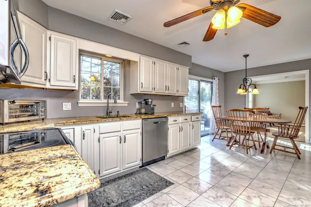 a kitchen with stainless steel appliances granite countertop a stove top oven a sink a dining table and chairs with wooden floor