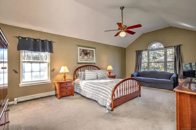 a bedroom with a bed couch chandelier and window