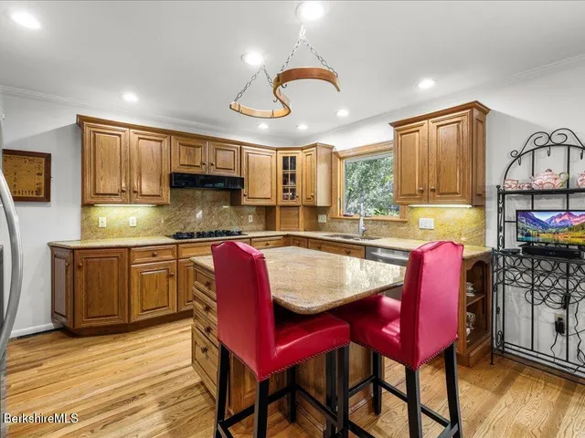 a kitchen with stainless steel appliances granite countertop a kitchen island a stove a table and chairs