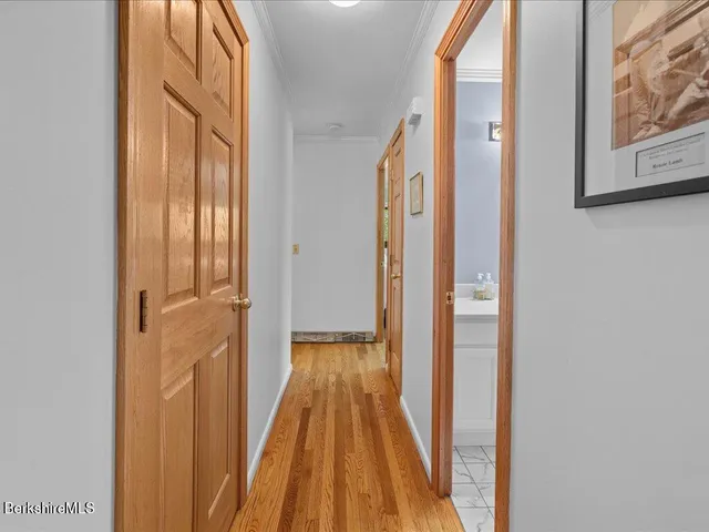 a view of a hallway with wooden floor and a bathroom