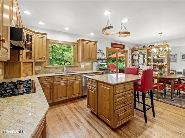 a kitchen with stainless steel appliances granite countertop a stove a sink dishwasher and a refrigerator with wooden floor