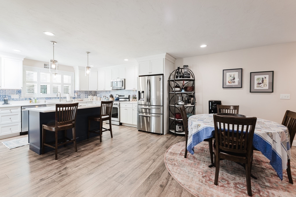 4 Sarah Beth Lane, Unit 1 Wareham, MA 02571 - Photo 19 of 42 a kitchen with stainless steel appliances a dining table chairs and wooden floor