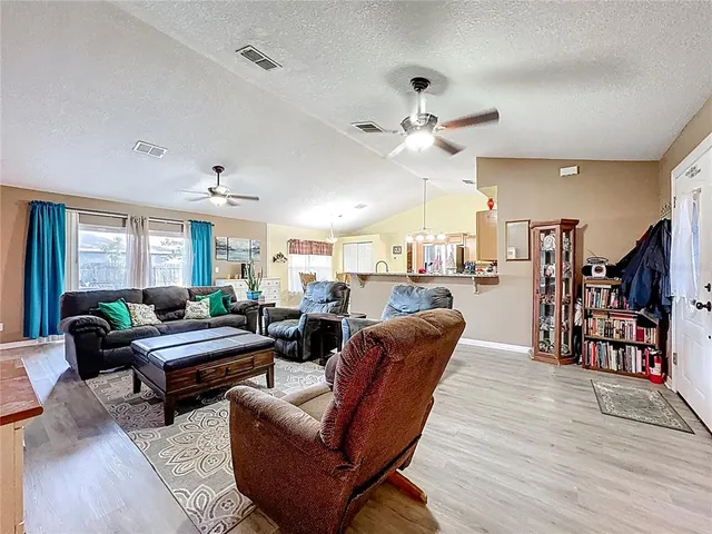 a living room with furniture kitchen view and a wooden floor