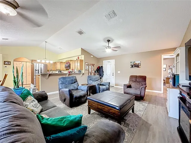 a living room with furniture kitchen view and a large window