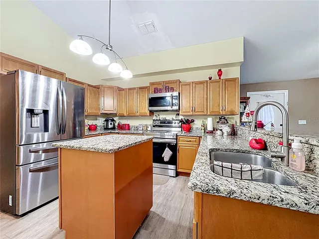 a kitchen with granite countertop a sink a counter top space stainless steel appliances and cabinets
