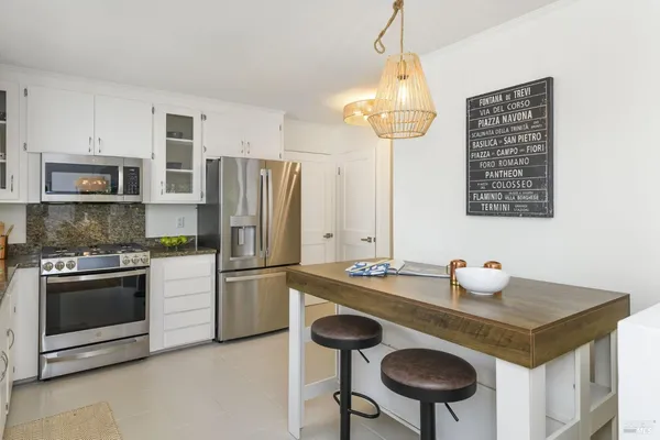 a kitchen with granite countertop stainless steel appliances a sink stove and cabinets