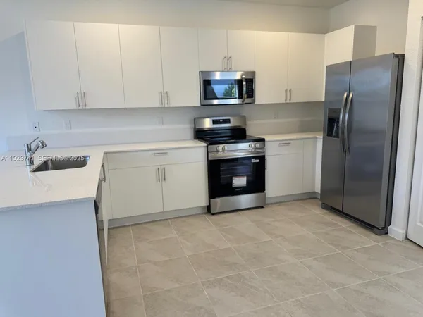 a kitchen with stainless steel appliances granite countertop a refrigerator sink and stove