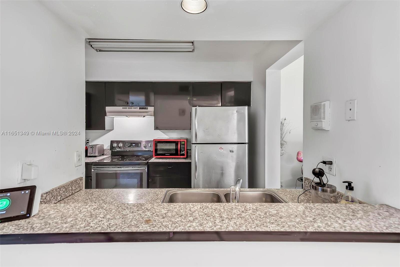 9823 Southwest 138th Avenue, Unit FC2L Miami, FL 33186 - Photo 15 of 28 a kitchen with granite countertop a refrigerator stove and sink