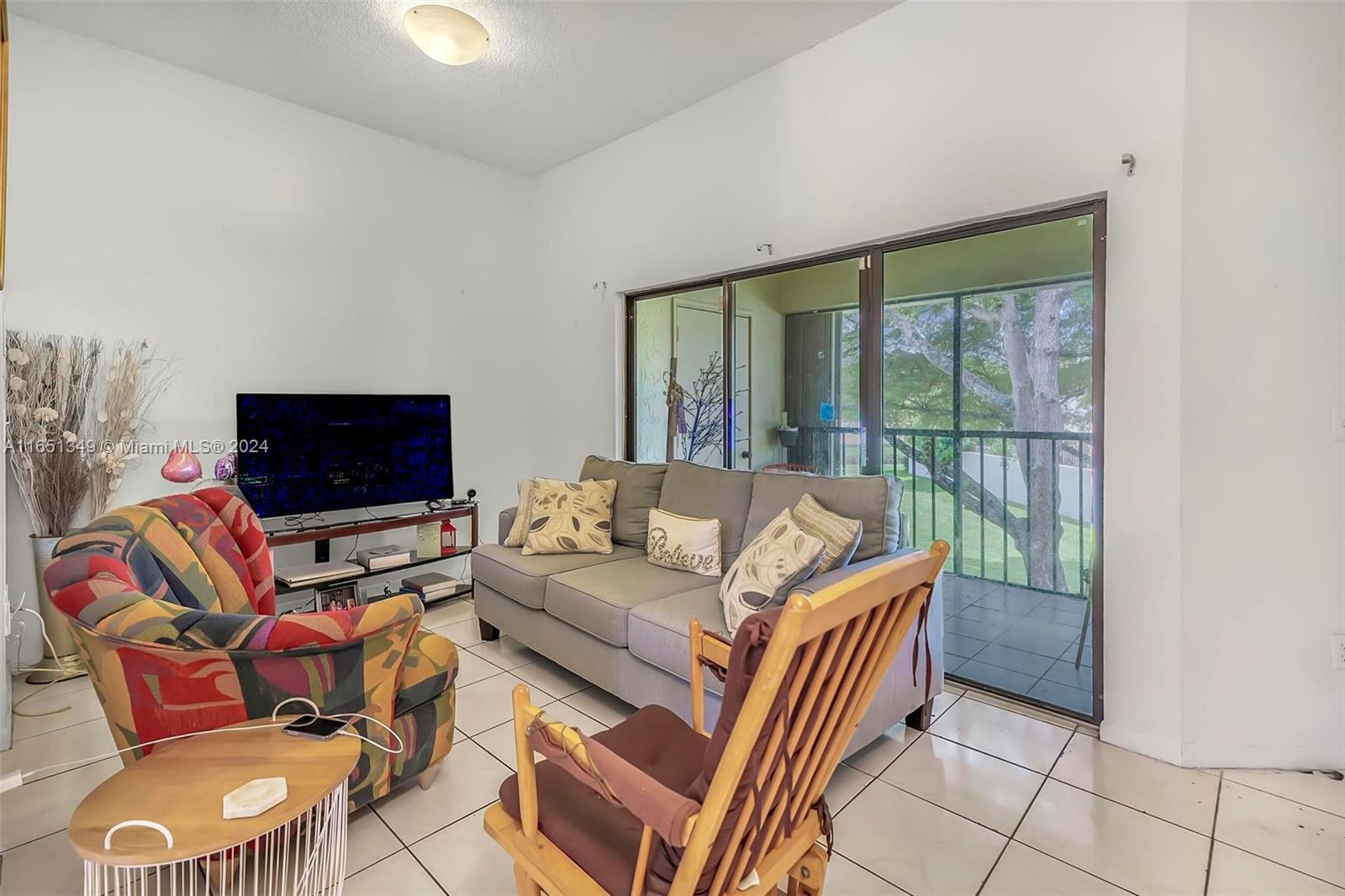 9823 Southwest 138th Avenue, Unit FC2L Miami, FL 33186 - Photo 7 of 28 a living room with furniture a flat screen tv and a floor to ceiling window