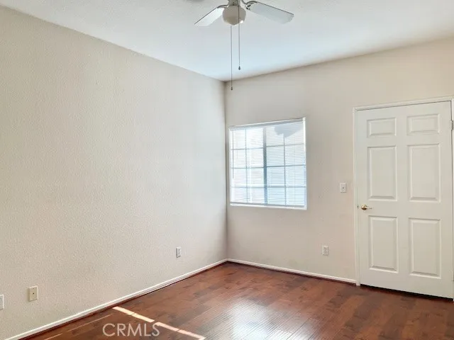 an empty room with a ceiling fan and wooden floor